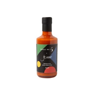 Può includere: Una bottiglia di vetro di salsa al peperoncino con tappo nero. L'etichetta presenta il testo "Chilli No. 5" e "Sriracha Cha-Cha-Cha" con forme geometriche colorate. La salsa è di un arancione vivace.