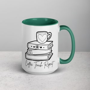 May include: White ceramic coffee mug with a green rim. The mug features a black and white illustration of a stack of books with a coffee cup on top. The text "Coffee Teach Repeat" is printed on the mug.
