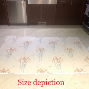 May include: A beige area rug with a floral pattern featuring brown and blue irises. The rug is laid out on a tiled floor in a kitchen.
