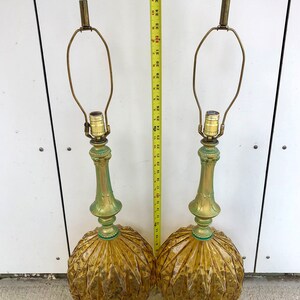 Pu&ograve; includere: Una coppia di lampade da tavolo con basi in vetro ambrato a coste e steli e basi in metallo dai toni verdi. Un metro a nastro giallo &egrave; posizionato tra le lampade, indicando un'altezza di circa 96,5 cm dalla base alla punta superiore.