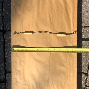 May include: A brown paper-covered frame with a wooden border and a hanging wire attached to the back.