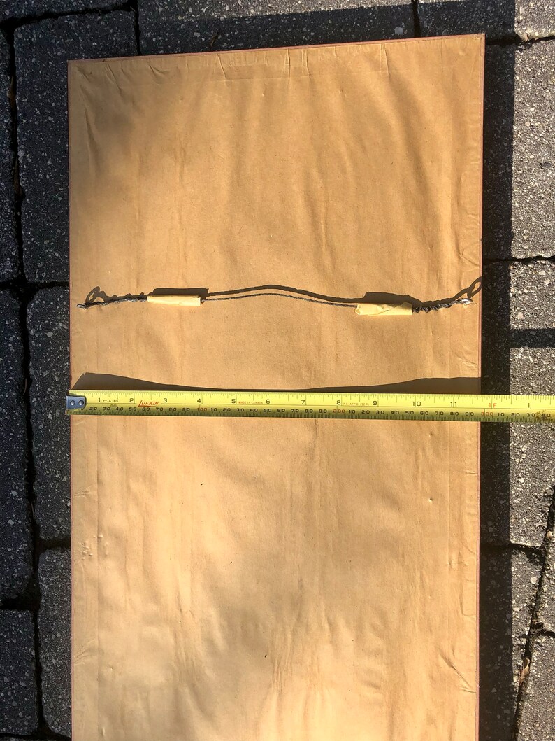 May include: A brown paper-covered frame with a wooden border and a hanging wire attached to the back.