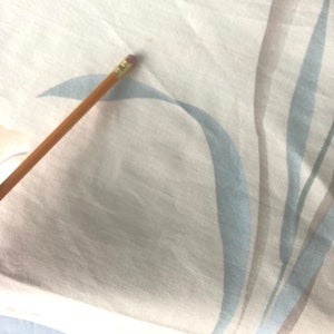 May include: A close-up of a white fabric with a light blue and brown striped pattern. The fabric has a subtle texture and a soft, natural feel.