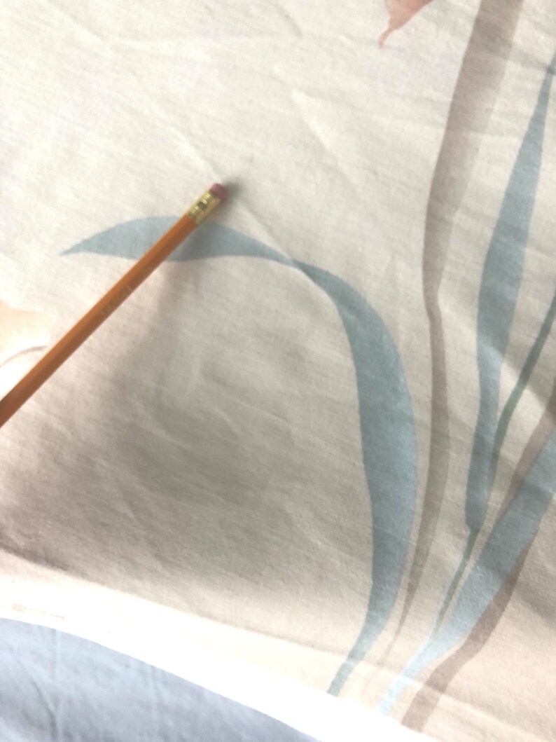 May include: A close-up of a white fabric with a light blue and brown striped pattern. The fabric has a subtle texture and a soft, natural feel.
