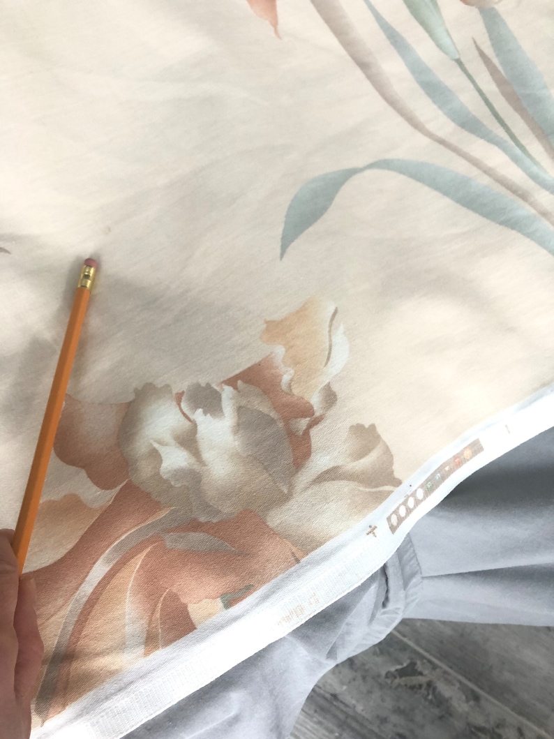 May include: Close-up of a beige fabric with a floral pattern. The fabric features large, abstract flowers in shades of brown, beige, and white. The fabric has a subtle sheen and a soft texture.