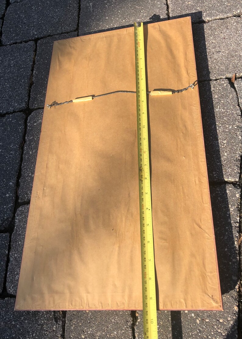 May include: The back of a framed picture with a brown mount and a red wood frame. A yellow measuring tape is placed along the right side of the frame. The tape measures 25.4 cm.