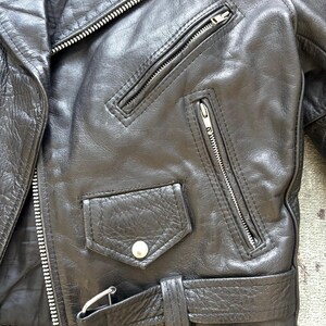 May include: Black leather motorcycle jacket with a zipper closure, a belt, and multiple pockets.