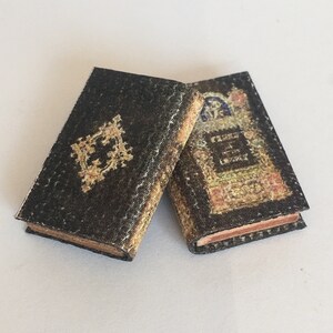 May include: Two miniature books with black covers and gold accents. One book has a floral design and the text "Cabinet of Love" on the cover. The other book has a gold design on the cover.