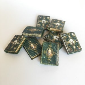 May include: A collection of eight miniature books with green covers and gold accents. The books have a vintage design with illustrations and text on the covers.