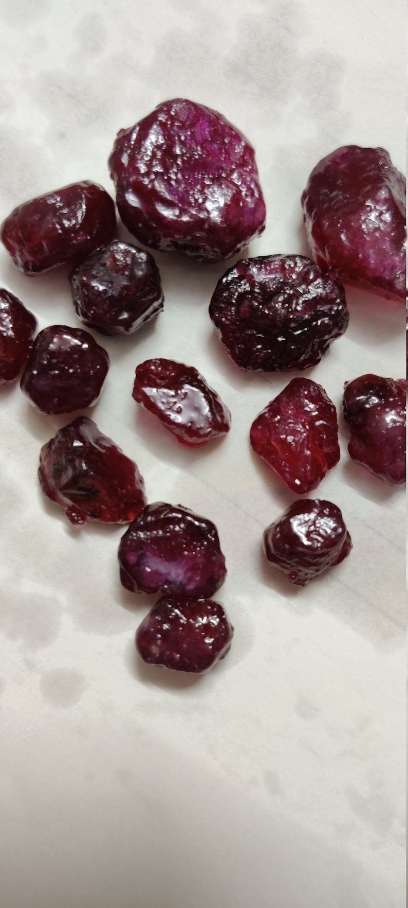 May include: A collection of small, dark purple gemstones, some with a shiny, polished finish, others with a more natural, rough texture.