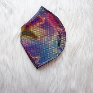May include: A holographic iridescent face mask with a black trim. The mask has a rainbow pattern with shades of pink, blue, green, and yellow.