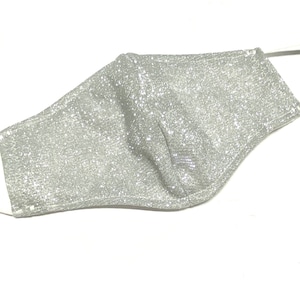May include: A silver glitter face mask with white elastic ear loops.