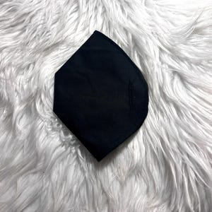 May include: A black fabric face mask with a diamond shape. The mask has a seam down the center.