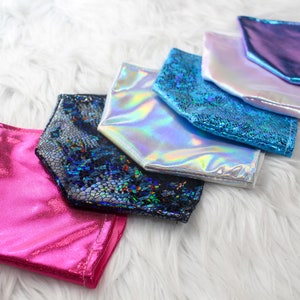 May include: A set of six iridescent face masks in various colors, including pink, blue, and silver. The masks are made of a shiny, metallic fabric and have a unique, textured design.