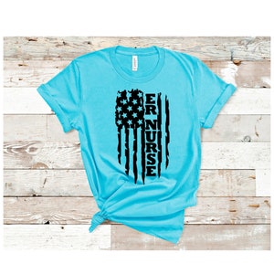 May include: A turquoise blue t-shirt with a black and white American flag design. The flag has the word "ER NURSE" written vertically down the middle.
