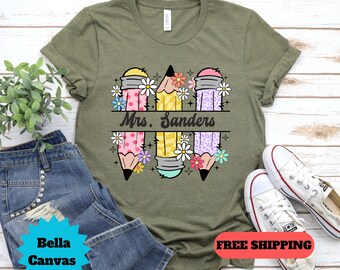 May include: A green t-shirt with a design of three colorful pencils with flowers and the text "Mrs. Sanders".