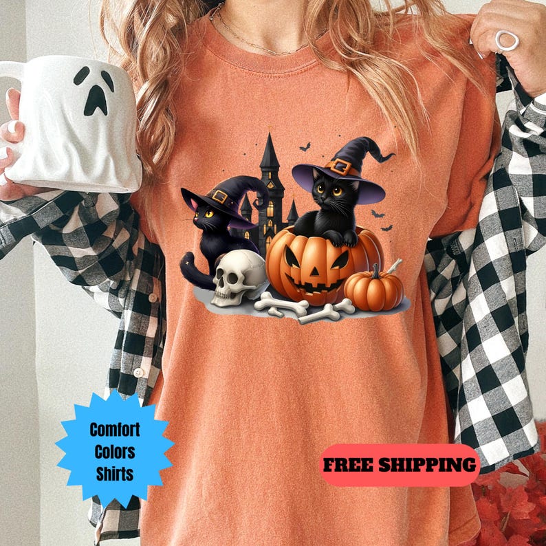 May include: Orange t-shirt with a black cat wearing a witch hat sitting inside a jack-o-lantern. The cat is holding a skull and bones. The text "FREE SHIPPING" is at the bottom of the image.
