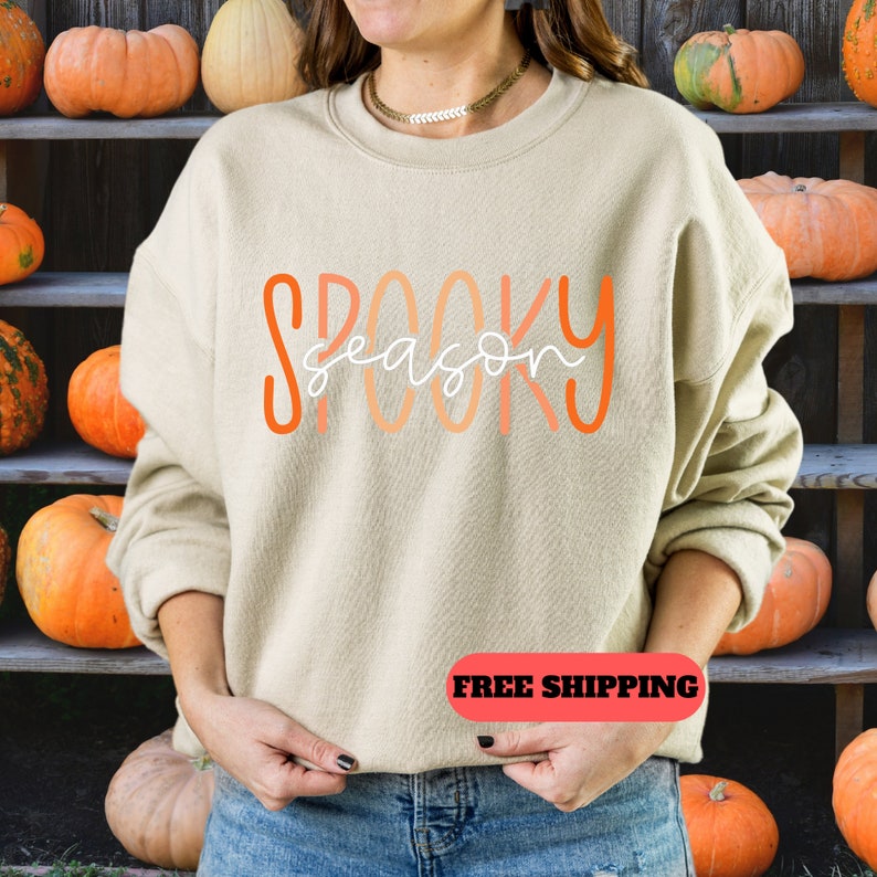 May include: A beige sweatshirt with the text "Spooky season" in orange and white lettering.