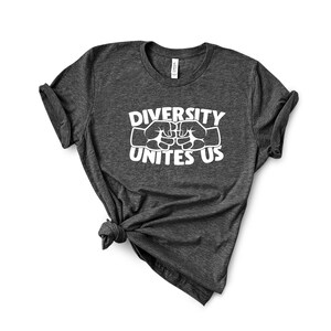 May include: Dark gray t-shirt with the text "DIVERSITY UNITES US" in white. The design features two fists bumping, symbolizing unity. The shirt is made of a soft material and has a classic crew neck.