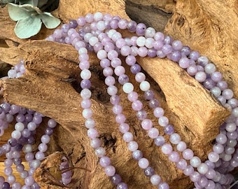 May include: A strand of smooth, round, light purple amethyst beads arranged in multiple loops. The beads vary slightly in shade from pale lavender to deeper violet tones, creating a consistent color gradient across the polished, spherical surfaces.