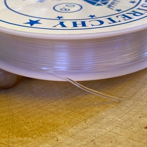 May include: A spool of clear elastic cord with a white label that says "Stretchy 0.8mm".
