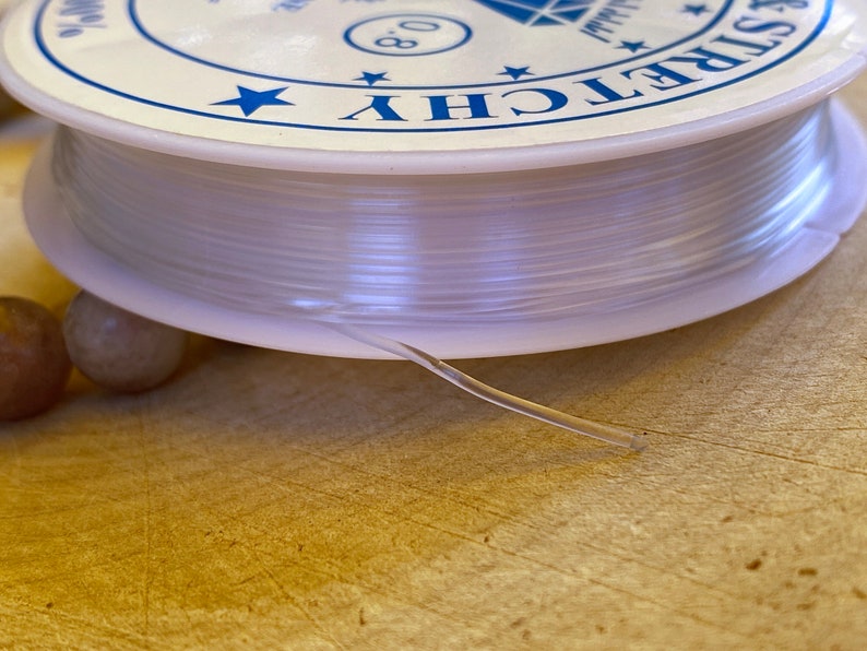 May include: A spool of clear elastic cord with a white label that says "Stretchy 0.8mm".