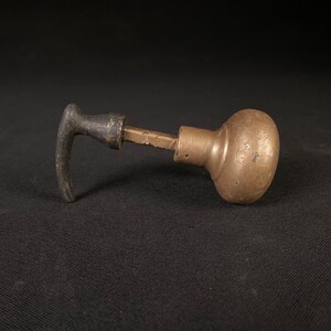 May include: A vintage brass door knob with a black metal lever handle. The knob is round and has a textured surface.