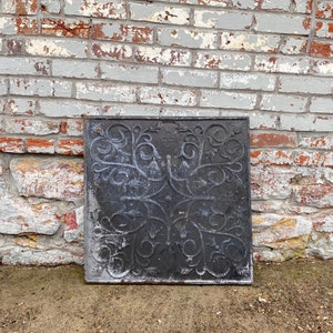 May include: A black metal decorative wall plaque with a floral design. The plaque has a distressed look and is made of cast iron.