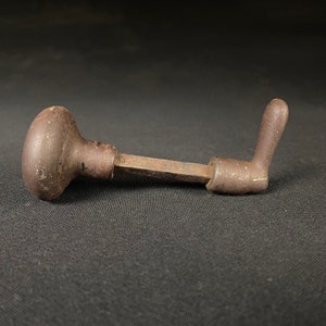 May include: A vintage, rusty, metal door knob with a round handle and a long, straight lever. The knob is brown and has a worn, aged look.
