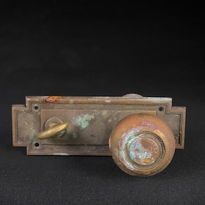 May include: Antique brass door knob and lock set with a round knob and a keyhole. The knob and lock plate have a patina finish.