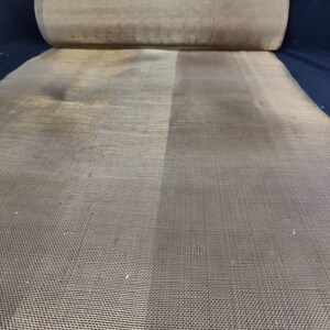 May include: A roll of brown mesh fabric with a fine weave. The fabric is rolled up and the end is visible.