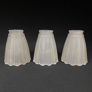 May include: Three white frosted glass lampshades with a scalloped edge and a pleated design.