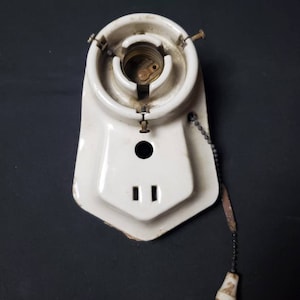 May include: White porcelain light fixture with a pull chain switch. The fixture has a round socket for a light bulb and two small holes on the bottom.