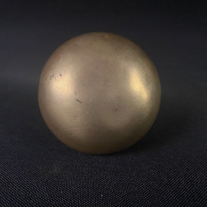 May include: A smooth, round, gold-colored metal sphere.