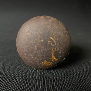 May include: A dark brown sphere with gold flecks and a rough texture.