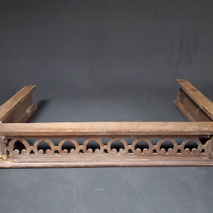 May include: A wooden fireplace mantel with a decorative carved design. The mantel is made of dark brown wood and has a rectangular shape.