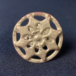 May include: Gold-toned metal decorative knob with a six-pointed star design. The knob has a circular shape and a raised, textured surface.