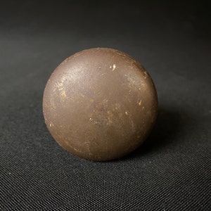 May include: A round, dark brown, ceramic knob with a slightly textured surface.