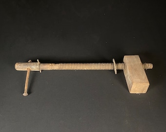 May include: A vintage wooden clamp with a threaded metal rod and a wooden handle. The clamp is made of unfinished wood and has a rustic look.