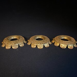 May include: Three gold-colored metal lamp finials with a scalloped edge and a textured surface.