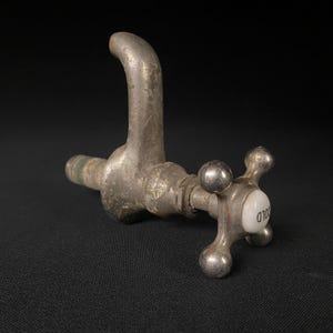 May include: An antique silver-toned faucet with a white porcelain handle marked "COLD".