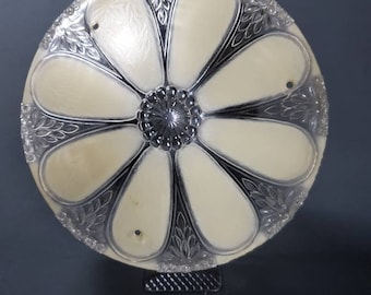 May include: A white glass ceiling light fixture with a flower design. The fixture has a clear glass center and six white petals with a textured design. The fixture has three holes for mounting.