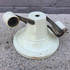 May include: A white ceramic light fixture with two sockets and a metal arm. The fixture has a decorative design around the base.