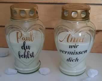 May include: Two glass heart-shaped candle holders with gold lids and white candles. The left holder has the text "Paul du fehlst" and the right holder has the text "Anni wir vermissen dich".