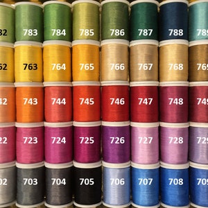 May include: A collection of 100 spools of thread in various colors, numbered 701 to 799. The spools are arranged in rows of ten, with each row containing a different color.