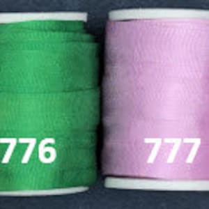May include: Six spools of thread in different colors. The spools are labeled with numbers 774, 775, 776, 777, 778, and 779.