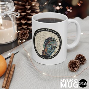 May include: White ceramic mug with a black handle. The mug features a circular design with a quote by Louise Gl&uuml;ck: "We look at the world once, in childhood. The rest is memory."