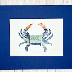 May include: A white matted print of a blue crab silhouette made from vintage postage stamps. The crab is outlined in red and blue stamps. The print is signed "JAG" in the bottom right corner.