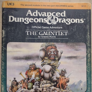 May include: The cover of a Dungeons & Dragons game module titled "The Gauntlet" by Graeme Morris. The cover features a fantasy illustration of a group of characters, including a large, muscular, red-haired ogre with a fierce expression.
