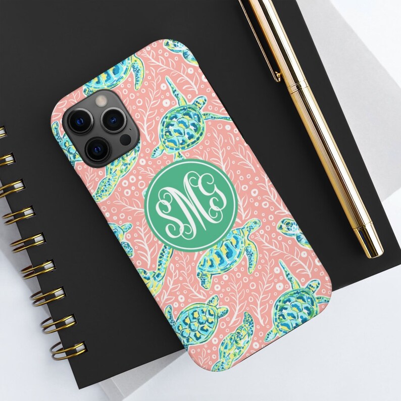 May include: A pink phone case with a white and green sea turtle pattern and a green monogram circle with the letters "SMC".